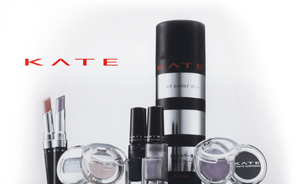 A wide variety of KATE cosmetics products in black and silver packaging against a grey background and “KATE” written in red.