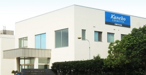 A white building, the Shanghai Kanebo Cosmetics Company factory, on the side of which a blue sign that reads, “Kanebo COSMETICS”, is visible.