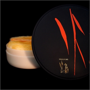 Round, black case showing artist Toko Shinoda’s calligraphy in red and the smaller gold logo, “Hinotori”, in English and Japanese.