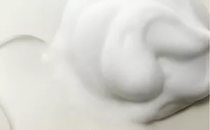 Flüssiges Shampoo und ein reichhaltiger Schaum nebeneinander, leicht vermischt