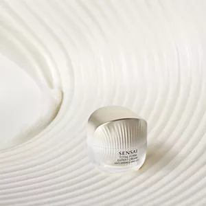 Frostet glasskrukke med gulllokket, vist på en bølgete kremaktig overflate.