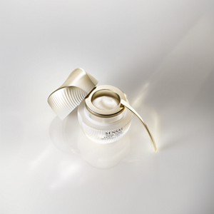 Frostet glasskrukke vist med gullokket og kremaktig tekstur på reflekterende overflate.