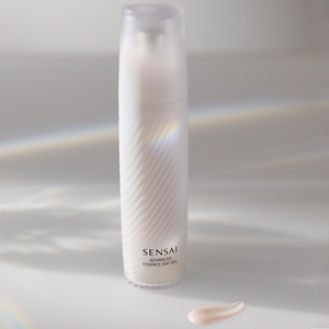 Biała butelka z pompką na jasnej powierzchni z delikatnymi smugami światła i niewielką ilością jasnoróżowego produktu z przodu