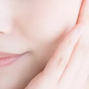 Nahaufnahme des unteren Gesichts einer Frau, deren Hand ihre Wange berührt