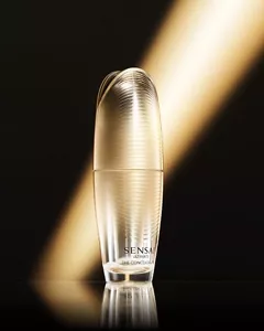 Shiny golden bottle illuminated by golden light against black background.