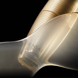 Golden glass bottle partially layered with transparent golden veil on black background