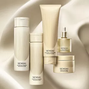 Five hair care items on a flowing beige-gold background with soft waves