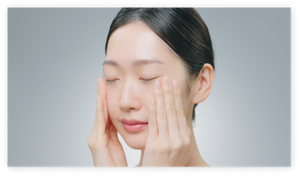 Applying Micro Mousse Treatment with both hands, smoothing over face in close-up