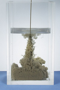 花王のコンクリート用界面活性剤型増粘剤の添加有・無でのセメントスラリーの水中での飛散の比較写真。左写真が無添加、セメントが飛散。