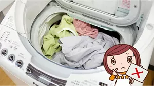 写真:悪い事例 洗濯槽からはみ出るほど洗濯物が入った洗濯機