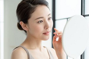 鏡を見て肌をチェックする女性