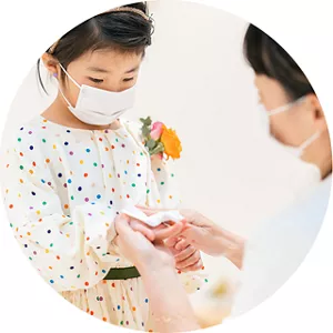 親子ともにマスクを着け、子供の手を拭く母親