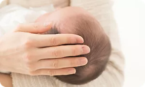 ママに頭を撫でられる赤ちゃん