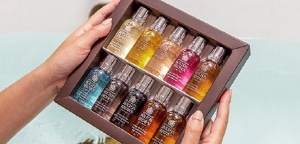 Well-manicured hands holding a box of 10 different travel-sized Molton Brown bath products.