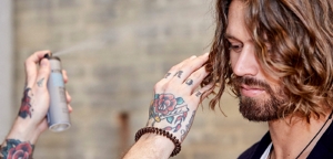 A close-up of a pair of hands styling a man's wavy hair.
