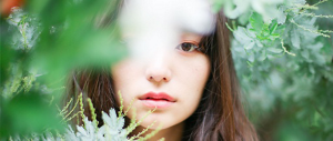 A young woman looking through leaves.