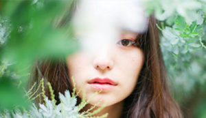 A young woman looking through leaves.