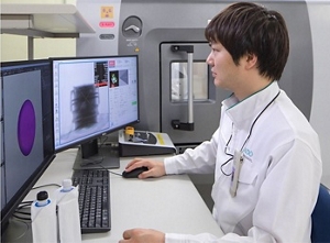 Photograph of a researcher observing a container using equipment for X-ray CT observation