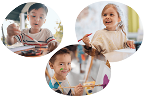 3人の子供たちが絵に関するさまざまな活動を行っています。1人はパレットに筆を浸し、もう1人はキャンバスに絵の具を塗り、もう1人はペンを持って机から顔を上げます。