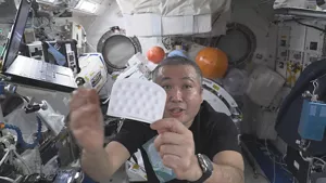 若田宇宙飛行士が「宇宙きぶん スペースシャンプーシート」の商品本体を持っている画像
