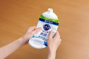 キュキュットecoペコボトルを両手で平らにつぶしている様子