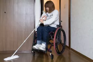 車いすに乗っている人がクイックルワイパーを使用して床を掃除