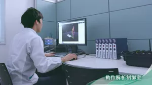 動作解析装置の制御室で男性がモニタに向かって作業している写真