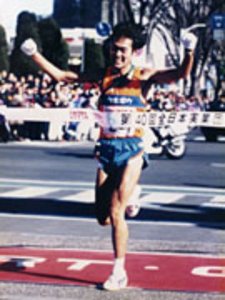 写真:手を上げてフィニッシュテープを切っている様子