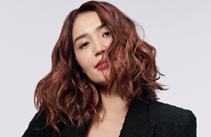 一位擁有美麗長髮的紅髮女性使用Goldwell頭髮產品。