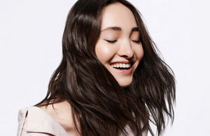 Smiling woman with dark brown hair and bright background