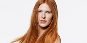 Serious looking woman with red straight hair and bright background