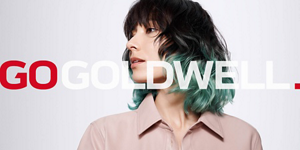 Woman with black and green hair in front of bright background and Go Goldwell logo in front