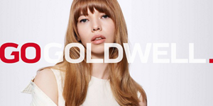 Woman with brown hair in front of bright background and Go Goldwell logo in front