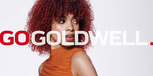 Woman with red hair in front of bright background and Go Goldwell logo in front