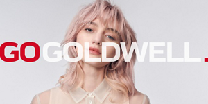 Woman with blonde hair in front of bright background and Go Goldwell logo in front