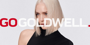Woman with red hair in front of bright background and Go Goldwell logo in front