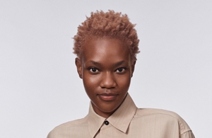 crnkinja kratke kose gleda pravo u kameru ispred sive pozadine