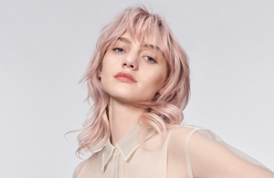 žena svetle puti sa plavom dugom kosom gleda pravo u kameru ispred sive pozadine