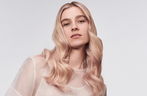 žena svetle puti sa plavom dugom kosom gleda pravo u kameru ispred sive pozadine