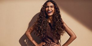 Two women with brown and red hair, using products from the Goldwell Muted Collection, standing in front of a grey background.