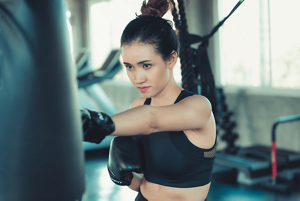 Woman boxing at the gym with black hair wearing a topknot