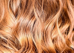 Back of a woman's head showing curly blonde balayage