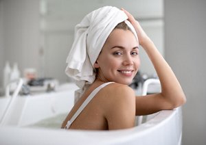 Smiling woman in the bath using a microfibre towel