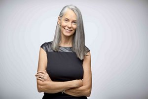 WOMAN WITH LONG GREY HAIR SMILING TO CAMERA