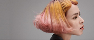 Woman with orange and pink bob shown from side with grey background