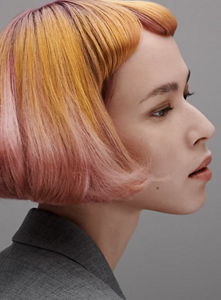 Woman with orange and pink bob shown from side with grey background