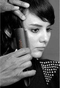 Coiffeur gaufrant les cheveux d’une femme à l’aide d’un fer à gaufrer VARIS et d’une brosse