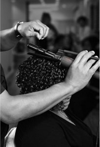Coiffeur utilisant un fer à boucler VARIS pour coiffer les cheveux d’une femme