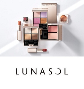 Two opened Lunasol makeup palette cases, one containing darker shades and one lighter, atop correlating powders in the background. 