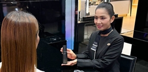 Two women smiling and looking at a tablet together while sitting at a table across each other in a store. 